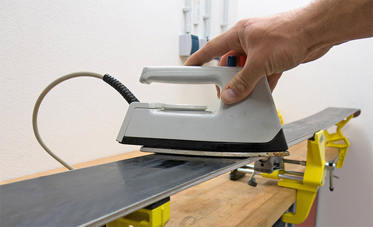 fartage de skis avec un fer Avec un fer à repasser, de la cire est appliquée sur un ski.